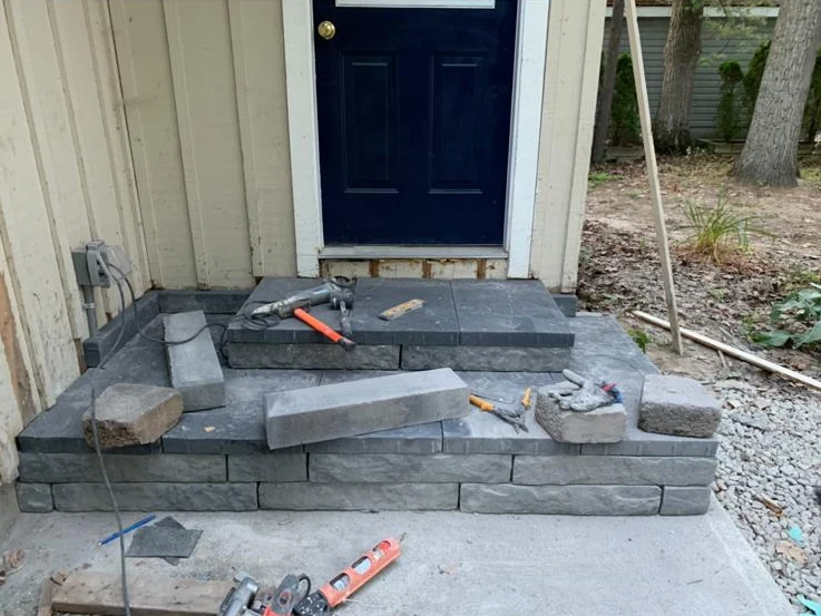 Stone entry steps under construction beside a blue front door