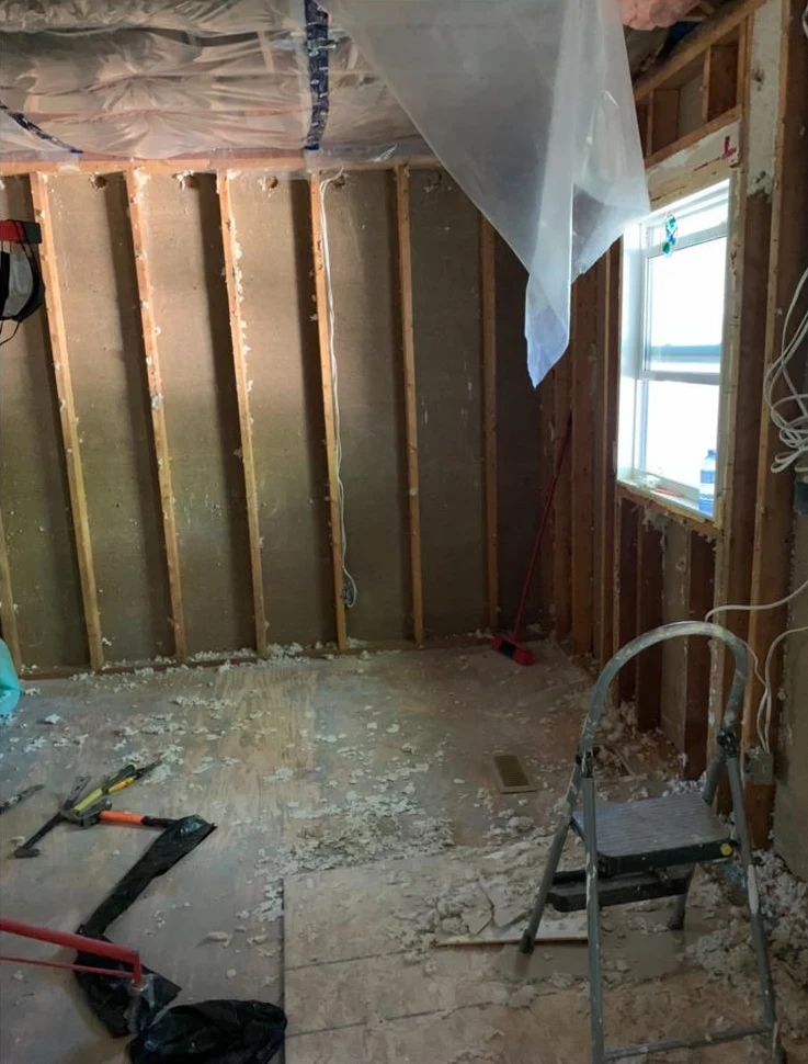 Room renovation in progress with exposed wall framing and a window